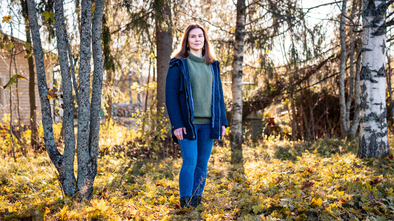 Nainen seisoo syksyisessä metsässä