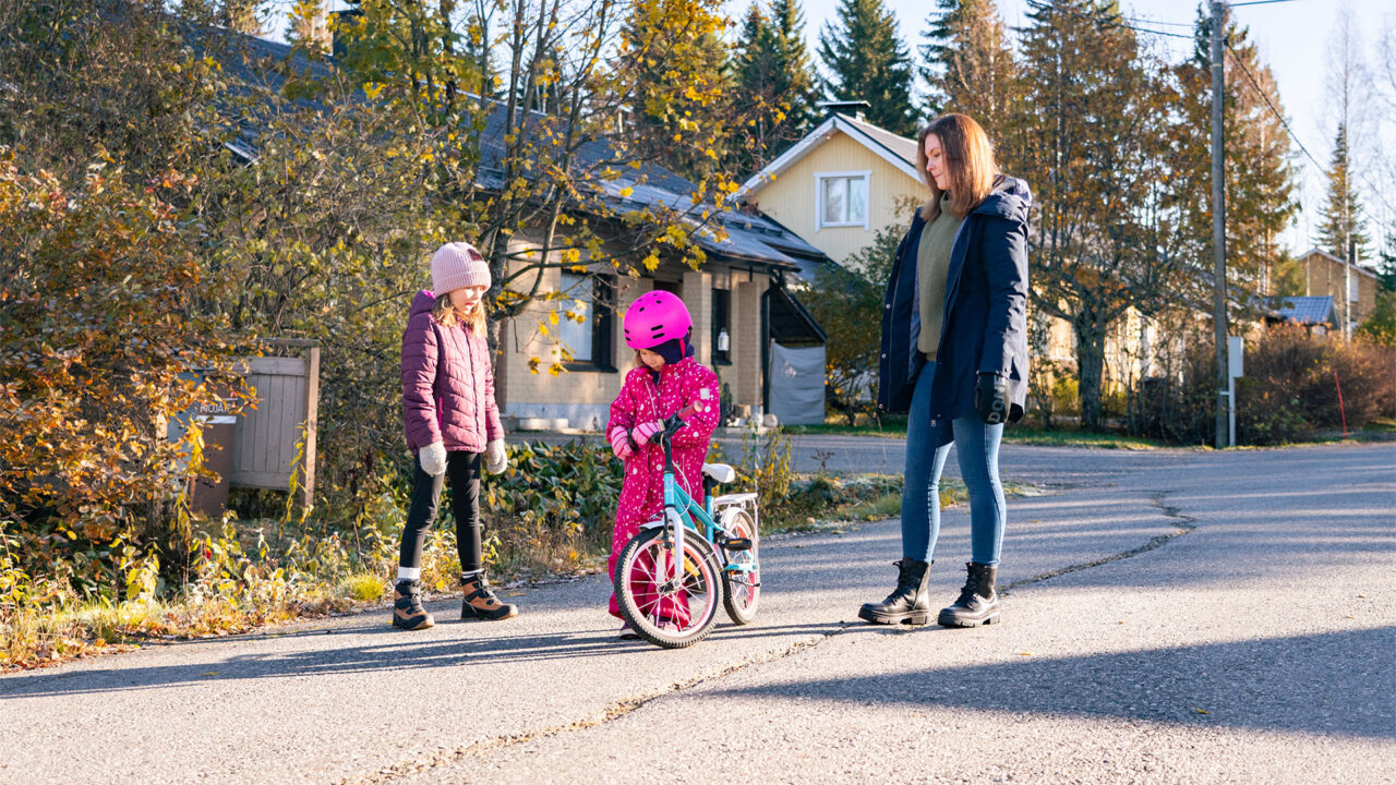 Nainen ja lapset seisovat tiellä